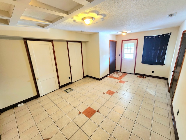 interior space with beamed ceiling, coffered ceiling, a textured ceiling, and light tile patterned floors