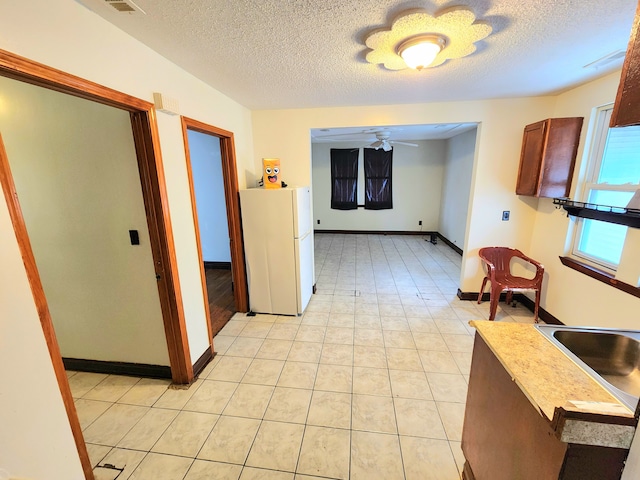 kitchen featuring white refrigerator, ceiling fan, and a textured ceiling