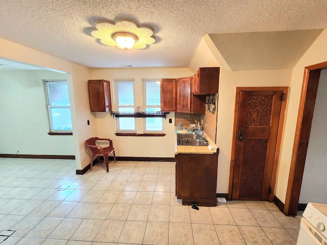 kitchen with sink, backsplash, light tile patterned floors, and a textured ceiling