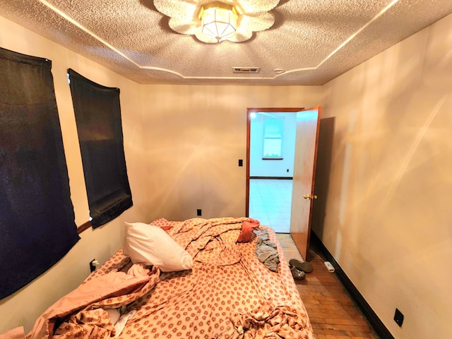 bedroom with hardwood / wood-style flooring and a textured ceiling