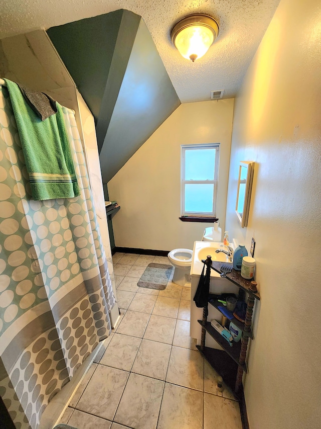 bathroom with curtained shower, sink, toilet, tile patterned floors, and a textured ceiling