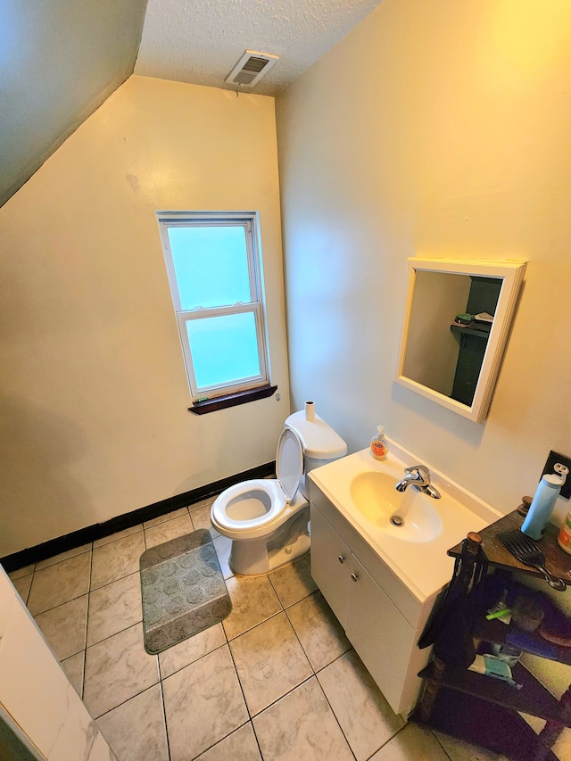 bathroom with tile patterned floors, toilet, lofted ceiling, a textured ceiling, and vanity