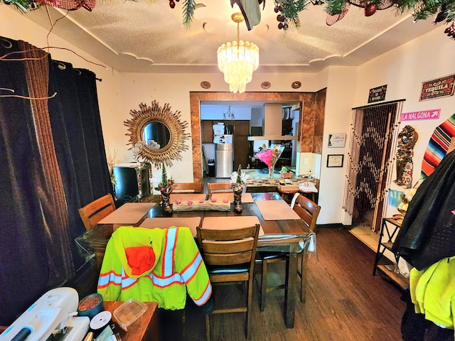 dining area featuring dark hardwood / wood-style floors, a notable chandelier, and a textured ceiling