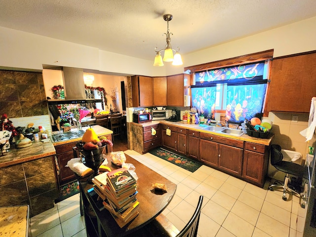 kitchen with light tile patterned floors, sink, hanging light fixtures, and a textured ceiling