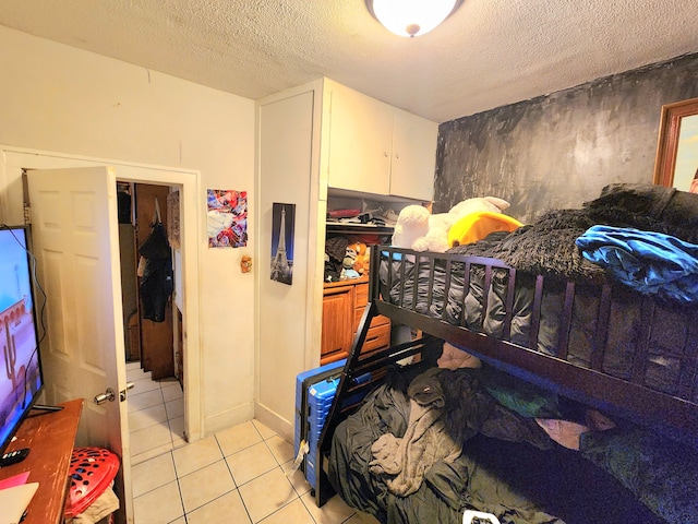 bedroom featuring light tile patterned floors, a textured ceiling, and a closet