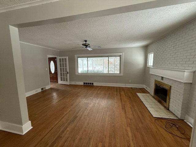 unfurnished living room with a fireplace, hardwood / wood-style floors, a textured ceiling, and ceiling fan