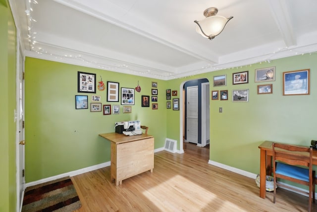 office with beam ceiling and light hardwood / wood-style flooring