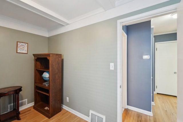 interior space featuring beamed ceiling, ornamental molding, and light hardwood / wood-style floors