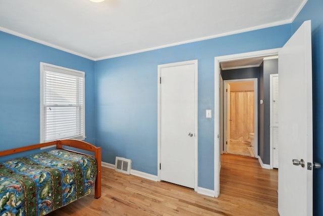 bedroom with crown molding and light wood-type flooring