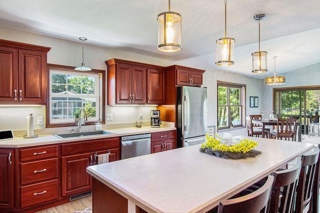 kitchen featuring a kitchen bar, a center island, hanging light fixtures, and appliances with stainless steel finishes