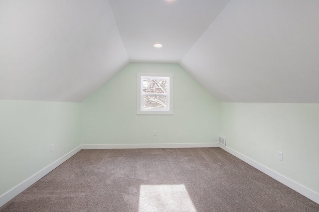 additional living space featuring vaulted ceiling and carpet floors