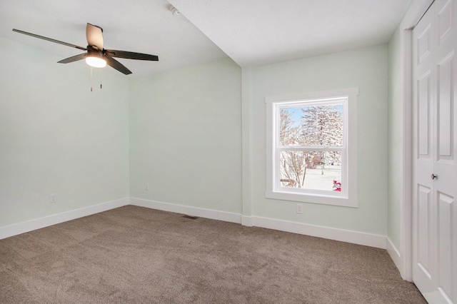 empty room featuring ceiling fan and light colored carpet