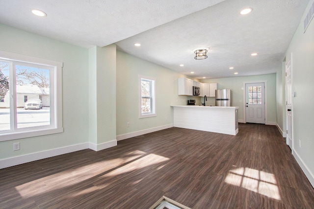 unfurnished living room featuring sink, a textured ceiling, plenty of natural light, and dark hardwood / wood-style flooring