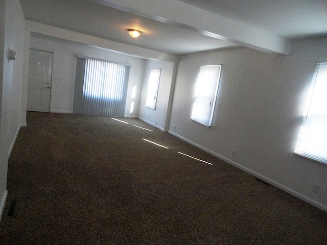 carpeted empty room featuring beamed ceiling and a wealth of natural light