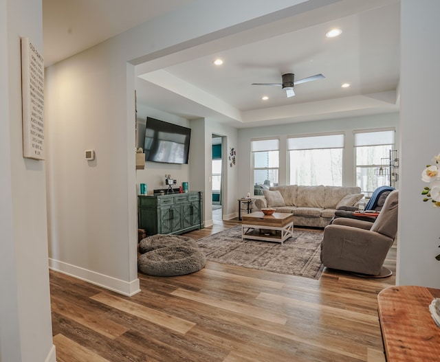 living room featuring ceiling fan, a raised ceiling, and hardwood / wood-style floors