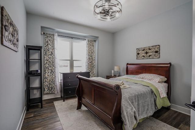 bedroom with a notable chandelier and dark wood-type flooring