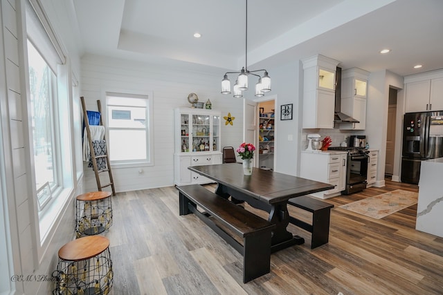 dining space with a tray ceiling, a chandelier, and light hardwood / wood-style floors