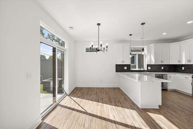 kitchen featuring white cabinetry, hanging light fixtures, kitchen peninsula, and a healthy amount of sunlight