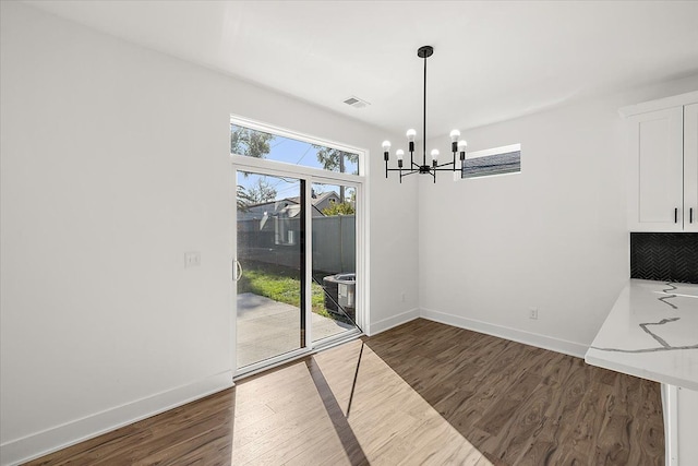 unfurnished dining area with dark hardwood / wood-style floors and an inviting chandelier