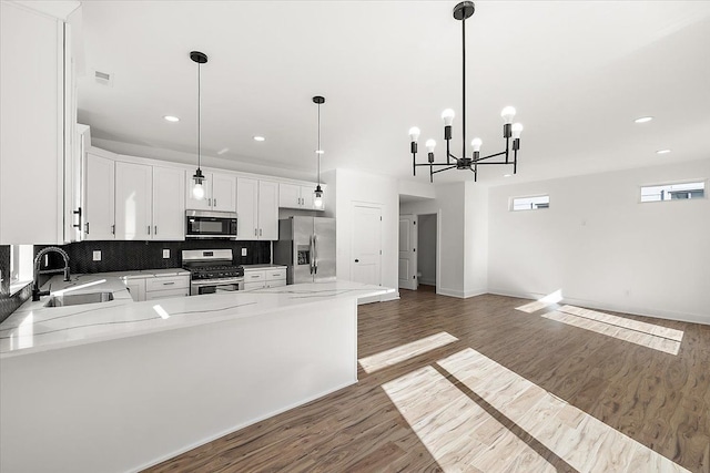 kitchen with pendant lighting, sink, tasteful backsplash, white cabinetry, and stainless steel appliances