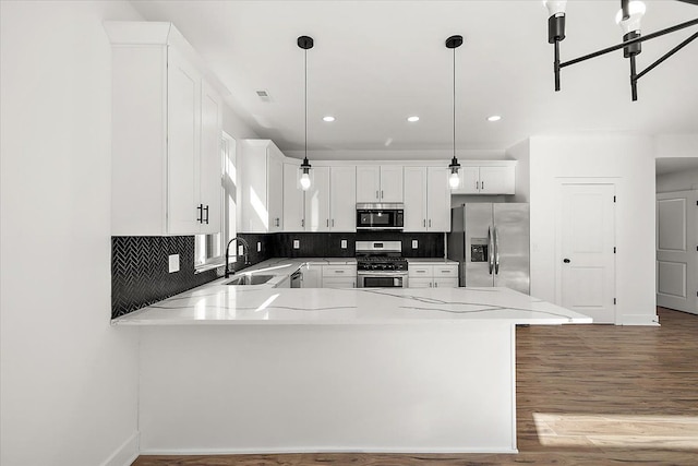 kitchen with pendant lighting, white cabinets, appliances with stainless steel finishes, sink, and kitchen peninsula