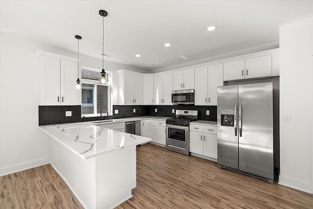 kitchen featuring white cabinets, pendant lighting, appliances with stainless steel finishes, and dark hardwood / wood-style flooring