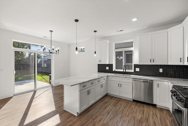 kitchen featuring kitchen peninsula, hanging light fixtures, appliances with stainless steel finishes, sink, and white cabinets