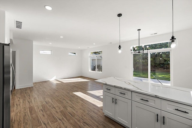 kitchen featuring decorative light fixtures, stainless steel refrigerator, light stone countertops, and dark hardwood / wood-style flooring