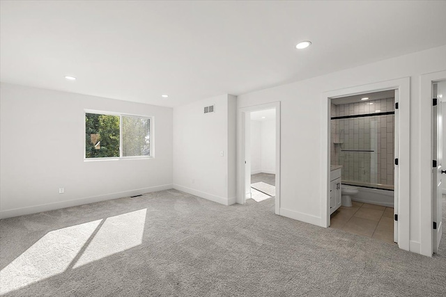 unfurnished bedroom featuring light colored carpet and ensuite bath