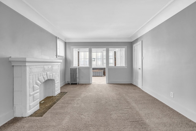 unfurnished living room with ornamental molding, a fireplace, radiator, and dark carpet