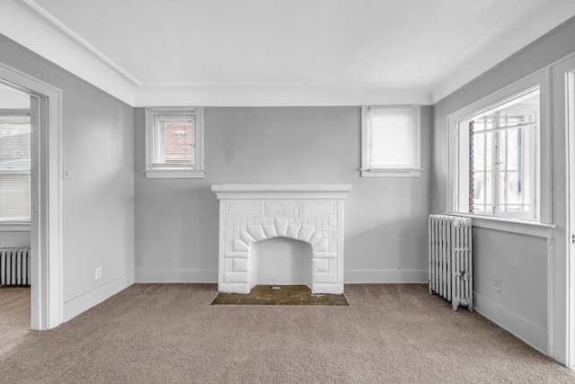 unfurnished living room with radiator, crown molding, light colored carpet, and a healthy amount of sunlight