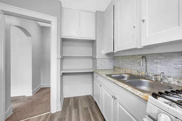 kitchen with tasteful backsplash, white cabinetry, sink, carpet floors, and white range with gas cooktop