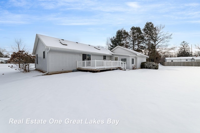 snow covered back of property with a deck