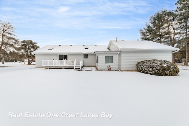 snow covered back of property with a wooden deck