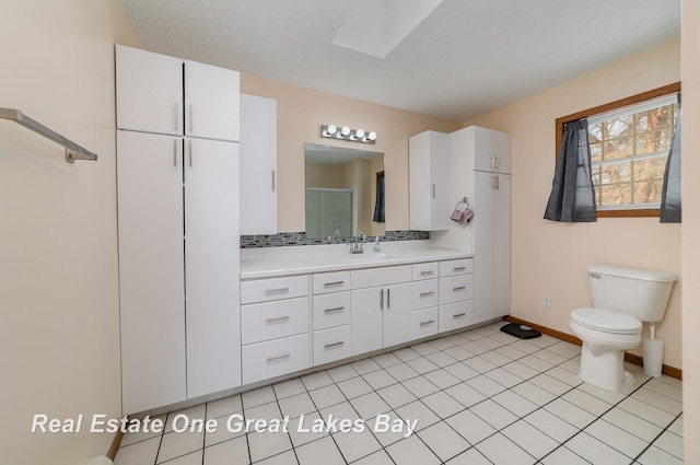 bathroom with toilet, a skylight, decorative backsplash, tile patterned flooring, and vanity