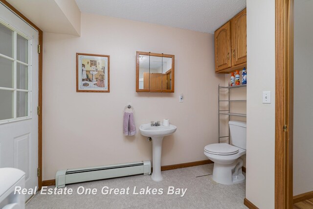 bathroom with sink, a textured ceiling, a baseboard heating unit, and toilet