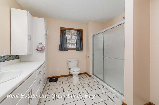 bathroom featuring vanity, a shower with shower door, tile patterned flooring, and toilet