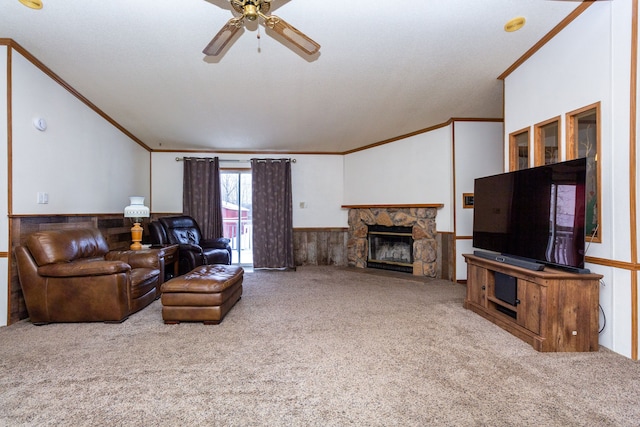 carpeted living room with ornamental molding, a stone fireplace, and ceiling fan