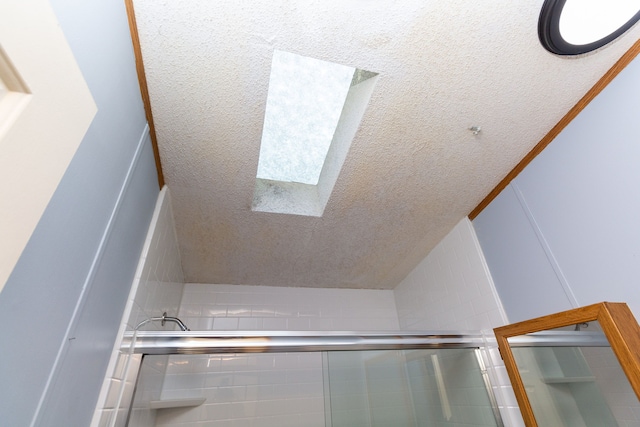 interior space featuring a skylight, a shower with shower door, and a textured ceiling