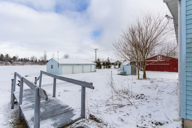 snowy yard with a garage and a storage unit