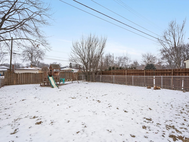 yard covered in snow featuring a playground