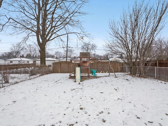 yard layered in snow featuring a playground