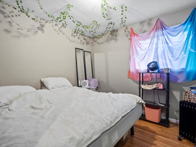 bedroom with wood-type flooring and radiator