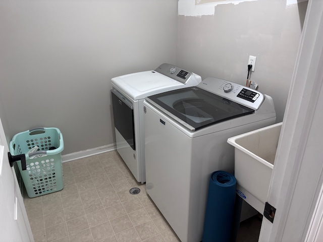 washroom featuring laundry area, baseboards, and washing machine and clothes dryer