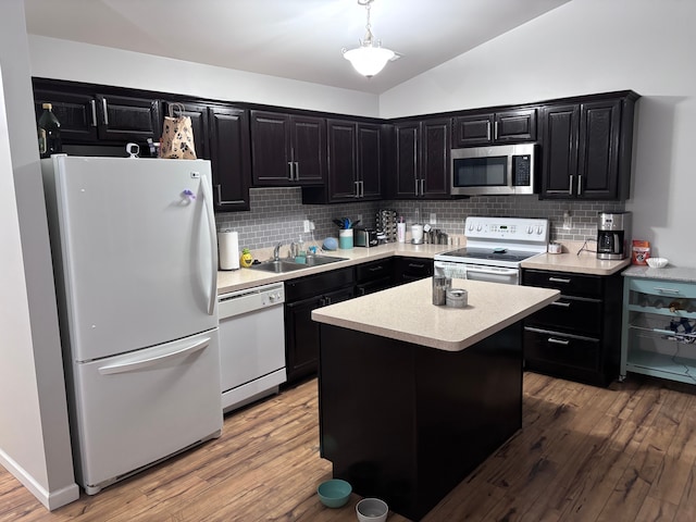 kitchen featuring white appliances, a sink, light countertops, a center island, and pendant lighting