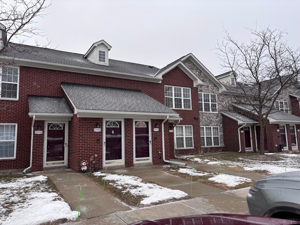 33540 Utica Rd Unit 13, Fraser, MI 48026 - townhome / multi-family property featuring stone siding, roof with shingles, and brick siding