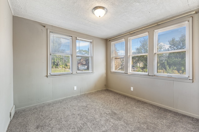 carpeted empty room featuring a textured ceiling