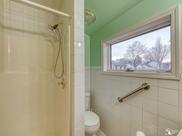 bathroom with a tile shower and toilet