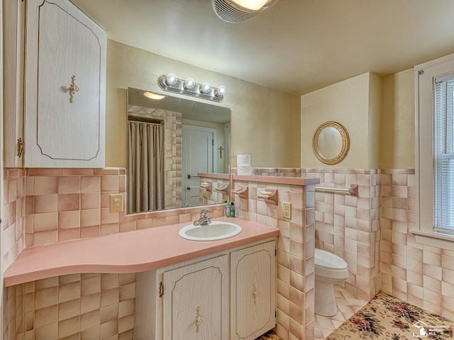 bathroom with tile walls, tile patterned flooring, vanity, a healthy amount of sunlight, and toilet