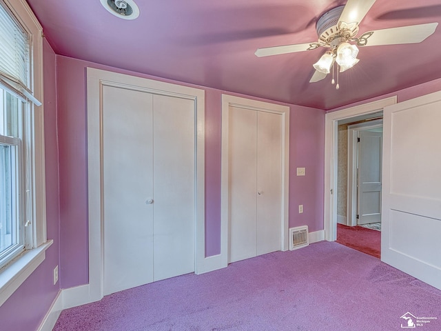 unfurnished bedroom with multiple closets, ceiling fan, and light carpet